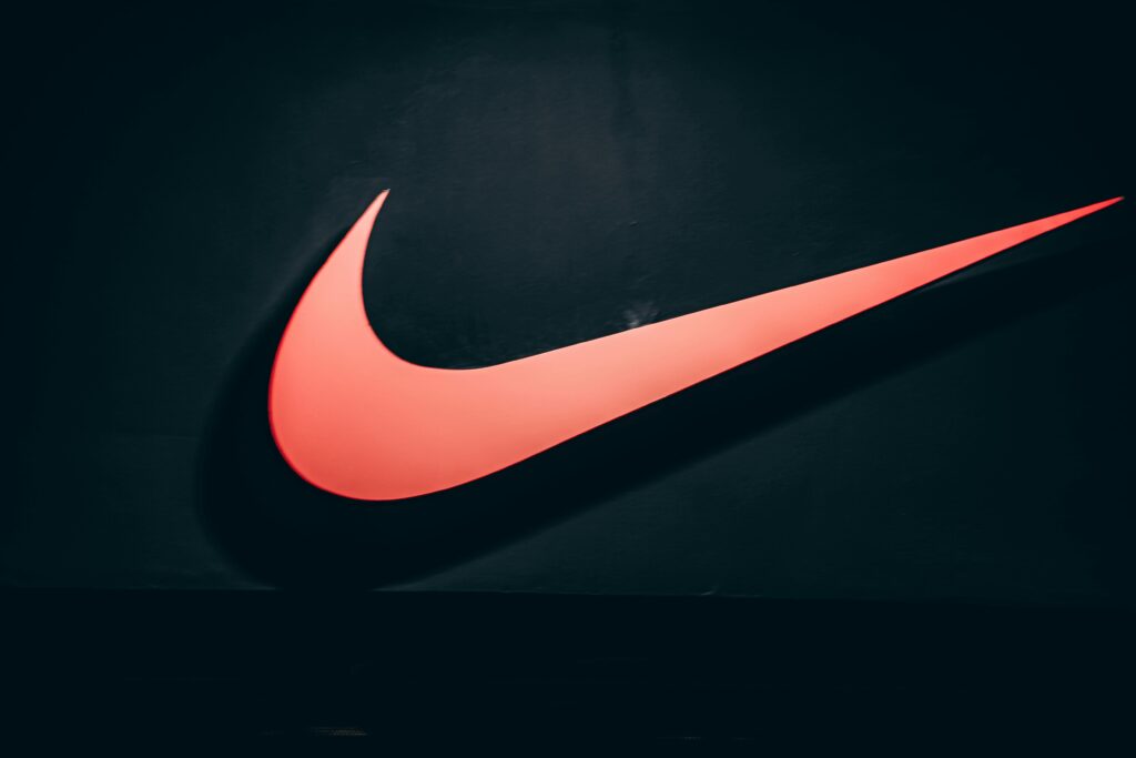 Vibrant red Nike swoosh logo displayed on a dark, minimalist backdrop symbolizing sports and lifestyle.